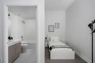 a white bathroom with a bed and a sink at Style & Comfort in the Heart of Toronto in Toronto
