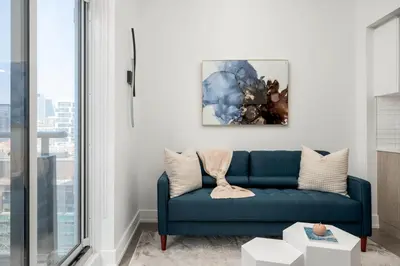a living room with a blue couch and a painting at Style & Comfort in the Heart of Toronto in Toronto