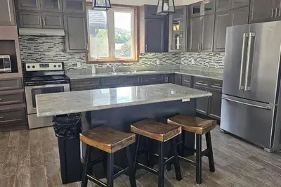 a kitchen with a counter and a refrigerator and stools at Grand 8-Bedroom Retreat 7 Baths Hot Tubs - Perfect Chalet in Blue Mountains