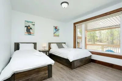 two beds in a room with a window at Grand 8-Bedroom Retreat 7 Baths Hot Tubs - Perfect Chalet in Blue Mountains