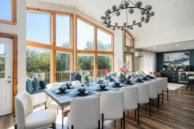 a dining room with a long table and white chairs at Large Chalet Hideaway - Hottub-SwimSpa - Sauna in Blue Mountains
