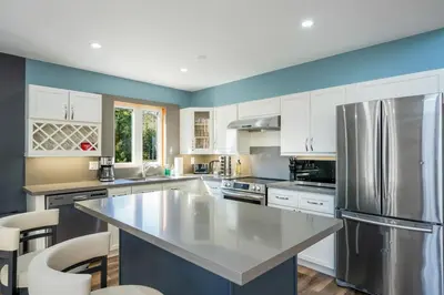 a kitchen with white cabinets and a stainless steel refrigerator at Large Chalet Hideaway - Hottub-SwimSpa - Sauna in Blue Mountains