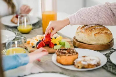 a person reaching for fruit on a table with a plate of food at Luma Lakehouse Icewine Lakefront | Deck + Hot Tub in St. Catharines