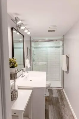 a white bathroom with a sink and a mirror at Luma Lakehouse Icewine Lakefront | Deck + Hot Tub in St. Catharines