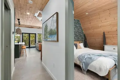 a bedroom with a bed and a kitchen in a house at Sauna Hot Tub Lake Off-Grid AFrame Retreat in Gravenhurst