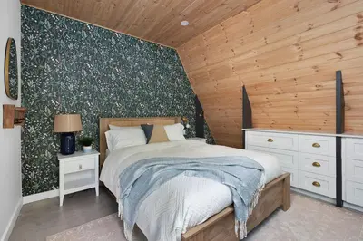 a bedroom with a bed and a wooden wall at Sauna Hot Tub Lake Off-Grid AFrame Retreat in Gravenhurst