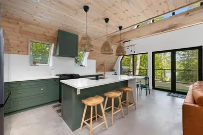 a kitchen with green cabinets and wooden ceilings at Sauna Hot Tub Lake Off-Grid AFrame Retreat in Gravenhurst
