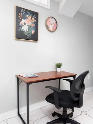 a desk with a chair and a clock on a wall at Roomy 1BD Apartment in Basement of House in Mississauga