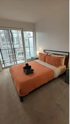 a bedroom with a large bed with an orange blanket at Nice view apartment office den in Port Hope