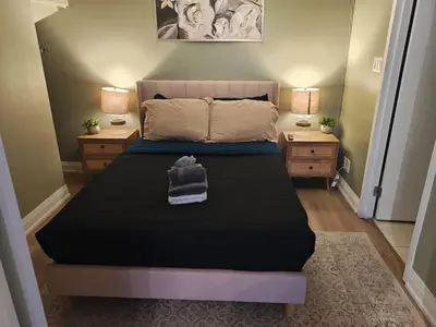 a bed in a room with two night stands and two lamps at Small Apartment for 2 in St. Catharines