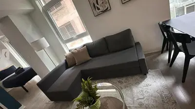 a living room with a black couch and a table at Condo with grey sofa bed in Port Hope