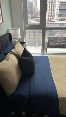 a blue couch with a pillow in a room with a window at Modern Group Condo in Port Hope