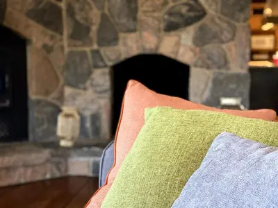 a pillow on a couch in front of a stone fireplace at Cajun Cabin Private Nature Resort in Minden