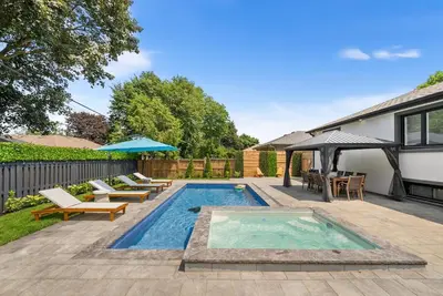 a backyard with a swimming pool with chairs and an umbrella at 5 Bedroom Luxury Spa Escape with Pool & Jacuzzi in Toronto