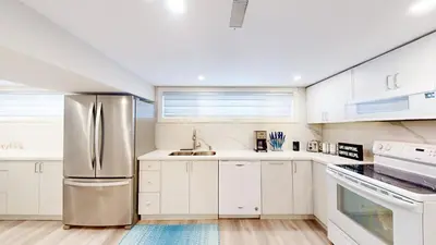 a kitchen with white cabinets and a stainless steel refrigerator at 5 Bedroom Luxury Spa Escape with Pool & Jacuzzi in Toronto