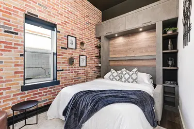 a bedroom with a large bed in a brick wall at The Brick & Beam Boutique Hotel in Collingwood