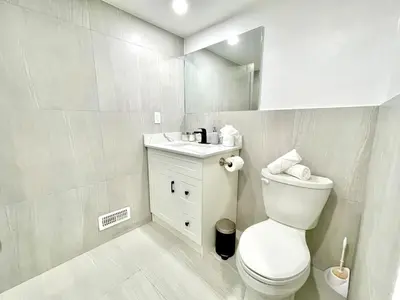 a white bathroom with a toilet and a sink at Violet Escape Modern Apt 1B 1B, Kitchen, Parking in Richmond Hill