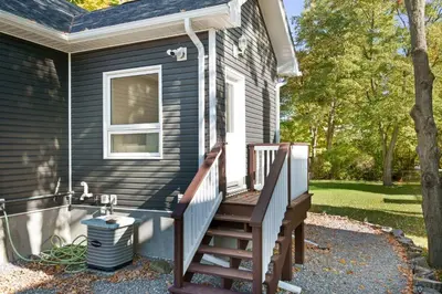 a house with a wooden staircase leading to a porch at Cozy Couple Retreat | 2 BDR APT | BBQ in Kawartha Lakes