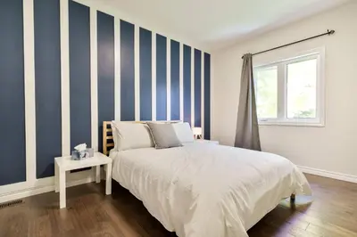 a bedroom with blue and white striped walls and a bed at Cozy Couple Retreat | 2 BDR APT | BBQ in Kawartha Lakes