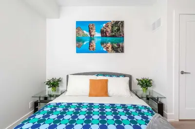 a bedroom with a bed and a painting on the wall at Westend Suites - Bright & Inviting 3BR Hotel near High Park in Toronto