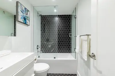 a white bathroom with a shower and a toilet at Westend Suites - Bright & Inviting 3BR Hotel near High Park in Toronto