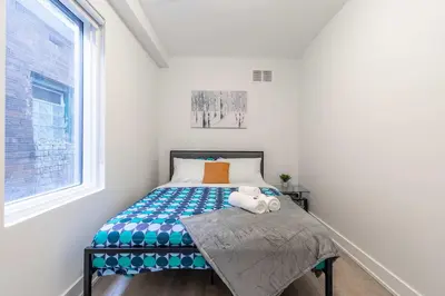 a small bedroom with a bed and a window at Westend Suites - Bright & Inviting 3BR Hotel near High Park in Toronto
