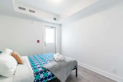 a white bedroom with a bed and a window at Westend Suites - Bright & Inviting 3BR Hotel near High Park in Toronto