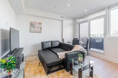 a living room with a black couch and a table at Westend Suites - Bright & Inviting 3BR Hotel near High Park in Toronto