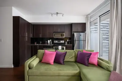a living room with a green couch with pink and purple pillows at Live the excitement Stay next to Scotiabank Arena! in Toronto
