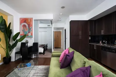 a living room with a green couch and a kitchen at Live the excitement Stay next to Scotiabank Arena! in Toronto