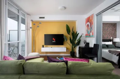 a living room with a green couch and a bedroom at Live the excitement Stay next to Scotiabank Arena! in Toronto