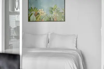a bedroom with a white bed with a picture on the wall at Beachside 2 Bedroom Suite with CN Tower, lake View, and Parking! in Toronto