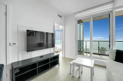 a living room with a tv and a couch and a table at Beachside 2 Bedroom Suite with CN Tower, lake View, and Parking! in Toronto