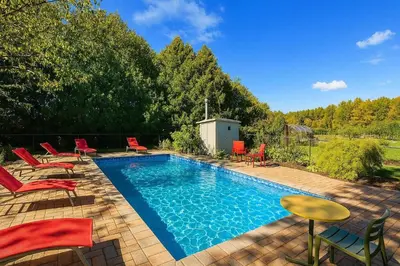 a swimming pool with red chairs and chairs next to it at 10 Acre Farmhouse with Pool + 5 Bedrooms/3 Baths in East Gwillimbury