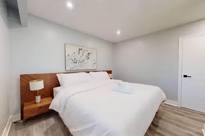 a bedroom with a large white bed and a lamp at 10 Acre Farmhouse with Pool + 5 Bedrooms/3 Baths in East Gwillimbury