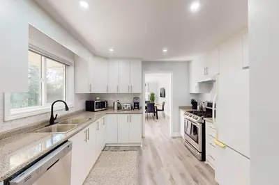 a white kitchen with a sink and a refrigerator at 10 Acre Farmhouse with Pool + 5 Bedrooms/3 Baths in East Gwillimbury