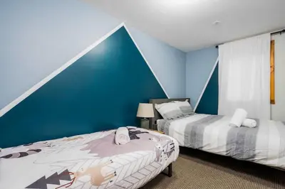 a bedroom with two beds and a blue wall at Large chalet 3 King bed Sauna-Hot Tubs Projector in Blue Mountains