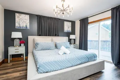 a bedroom with a bed with blue sheets and a chandelier at Large chalet 3 King bed Sauna-Hot Tubs Projector in Blue Mountains