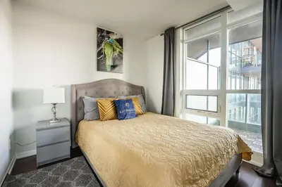 a bedroom with a bed with a large window at Panoramic 2 Bedroom Condo with Terrace Fort York Downtown Toronto in Toronto