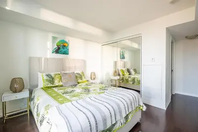 a white bedroom with a bed and a mirror at Panoramic 2 Bedroom Condo with Terrace Fort York Downtown Toronto in Toronto