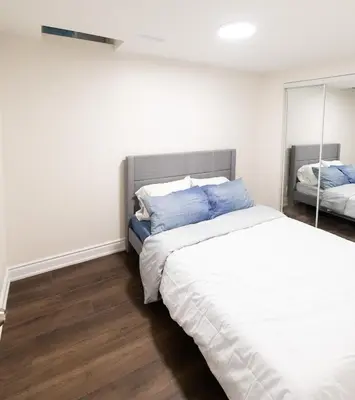 a bedroom with a large bed and a mirror at New Basement Apartment with parking in Oakville