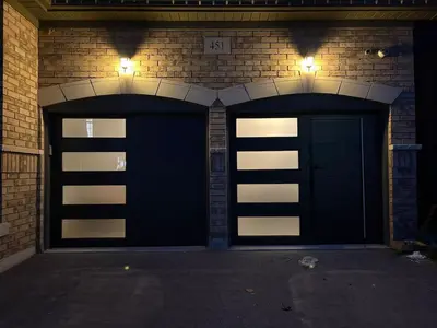 two garage doors in a brick building at night at New Basement Apartment with parking in Oakville