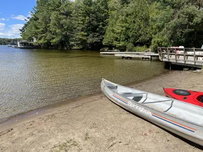 a boat sitting on the shore of a lake at Stunning Lakeview Muskoka Pier 100 Resort in Port Carling