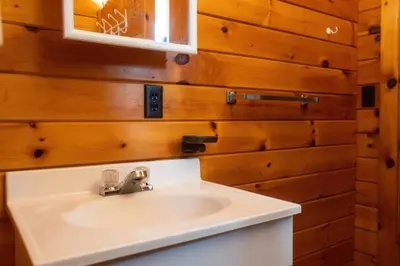 a bathroom with a white sink and wooden walls at Stunning Lakeview Muskoka Pier 100 Resort in Port Carling