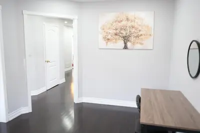 a white room with a table and a tree on the wall at Large Family Favorite Spacious 6-Bedroom Home in Brampton