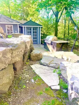 a backyard with a stone wall and a boat in front of a house at The Serenity Home Pool/Yoga/Game Room by the Lake in Mississauga