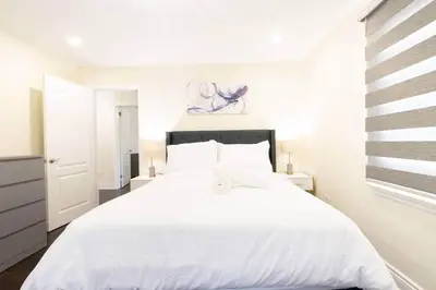 a white bedroom with a large white bed at The Serenity Home Pool/Yoga/Game Room by the Lake in Mississauga