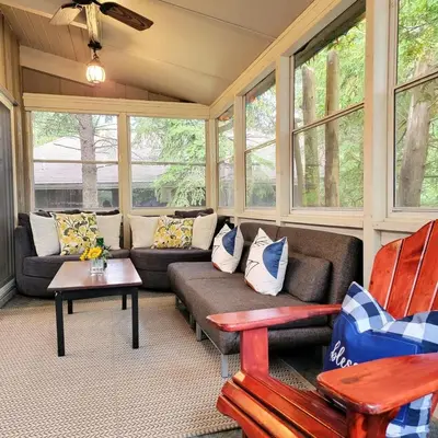 a screened in porch with a couch and chairs at Cozy upgraded Chalet Hot Tubs Sauna Fireplace in Blue Mountains