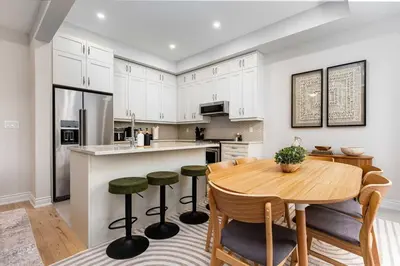 a kitchen with white cabinets and a wooden table at Elegant Five Bedroom Home Designed for Comfort and Space in Oakville