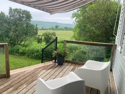 a deck with white chairs and a view of a field at Beaver Valley Farmhouse with Pool & Stunning Views in Kimberley